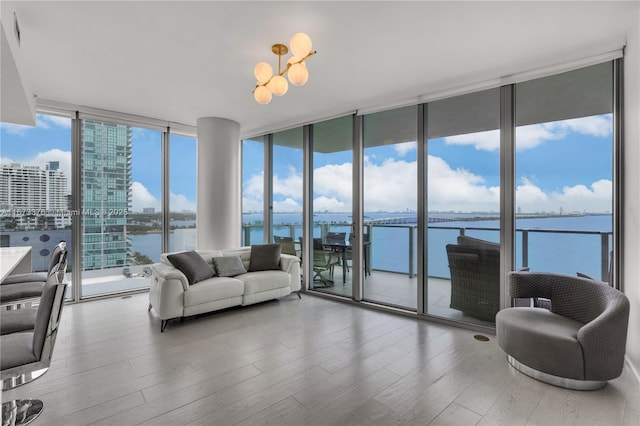 living room with floor to ceiling windows, a water view, and a healthy amount of sunlight