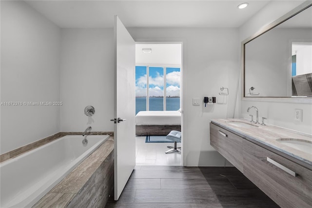 bathroom featuring vanity, a water view, and tiled tub