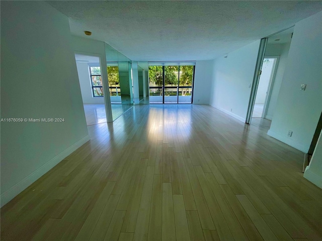 unfurnished room featuring a textured ceiling and light hardwood / wood-style flooring