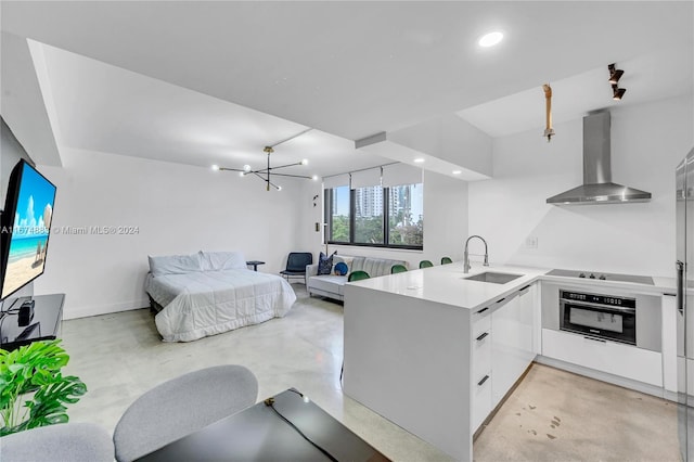 kitchen featuring wall chimney range hood, oven, sink, kitchen peninsula, and white cabinetry