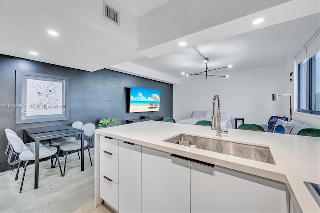 kitchen with white cabinets, a chandelier, and sink