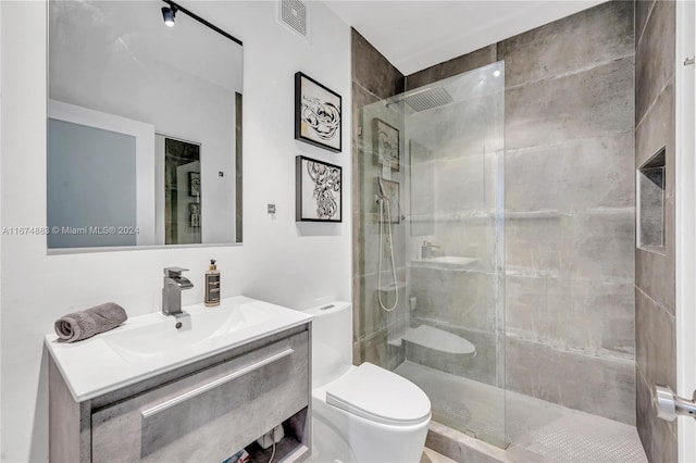 bathroom featuring a shower with door, vanity, and toilet