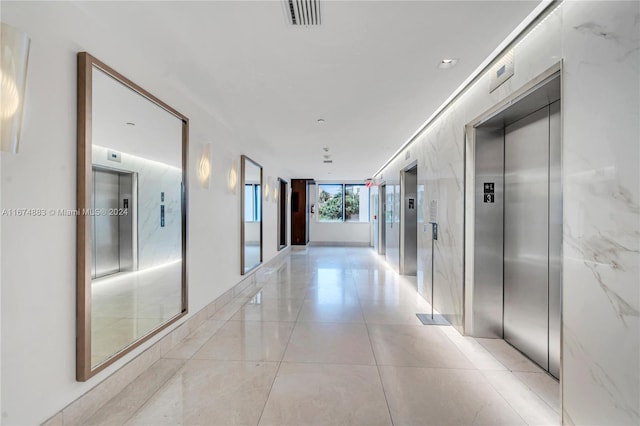 corridor featuring elevator and light tile patterned floors