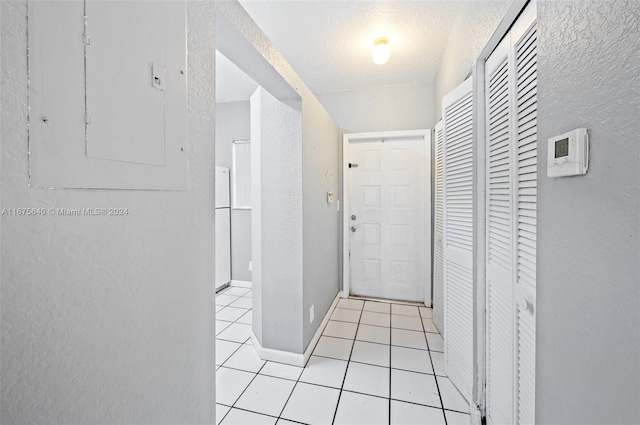 corridor with electric panel, a textured ceiling, and light tile patterned flooring