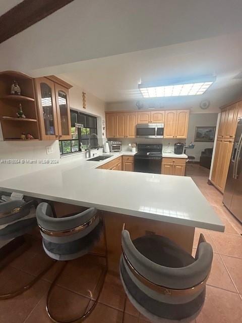 kitchen with kitchen peninsula, stainless steel appliances, sink, a kitchen bar, and light tile patterned floors