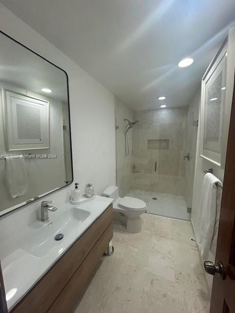 bathroom with vanity, toilet, and a tile shower