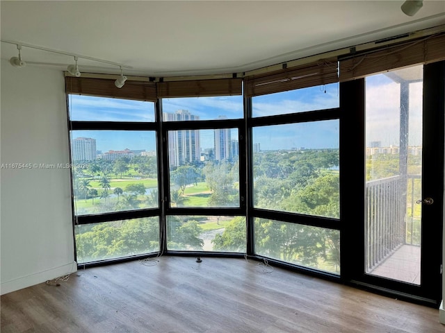 unfurnished sunroom featuring a view of city, rail lighting, and plenty of natural light