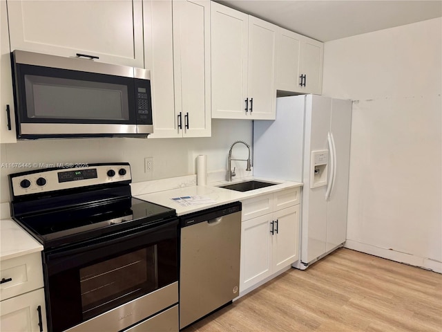 kitchen featuring stainless steel appliances, light countertops, white cabinetry, and a sink