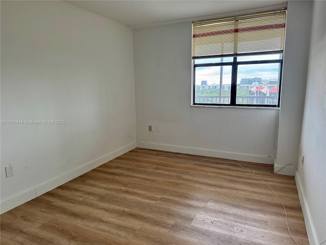 spare room with baseboards and light wood finished floors