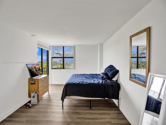 bedroom with baseboards, multiple windows, and light wood-style floors