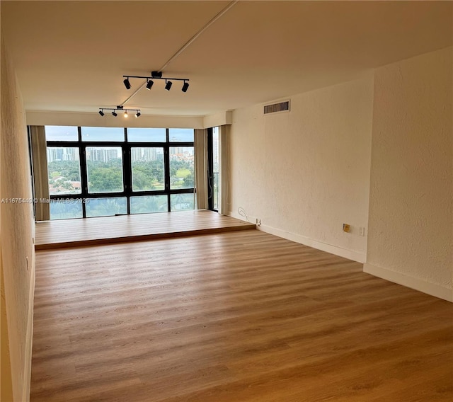 spare room with hardwood / wood-style floors and track lighting