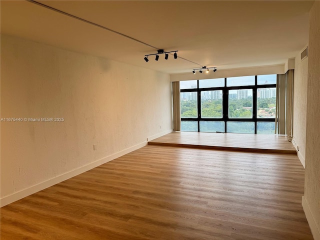 unfurnished room featuring hardwood / wood-style floors and track lighting