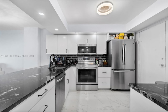 kitchen with dark stone counters, white cabinets, appliances with stainless steel finishes, and sink