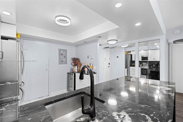 workout area with dark wood-type flooring, a tray ceiling, and sink