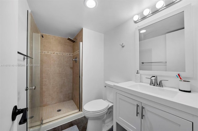 bathroom featuring vanity, hardwood / wood-style flooring, a shower with shower door, and toilet