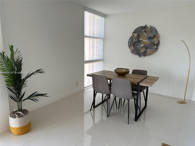 dining space featuring light tile patterned floors and a wall of windows