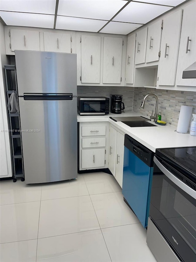 kitchen featuring sink, a drop ceiling, stainless steel appliances, backsplash, and light tile patterned floors