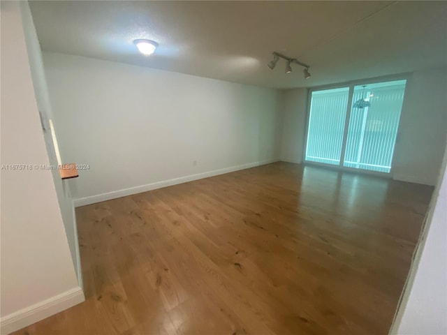 unfurnished room with track lighting and hardwood / wood-style flooring