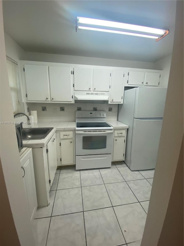 kitchen with light tile patterned floors, sink, white appliances, and white cabinetry