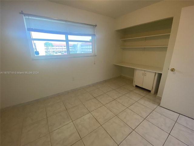 interior space featuring a closet, built in desk, and light tile patterned floors