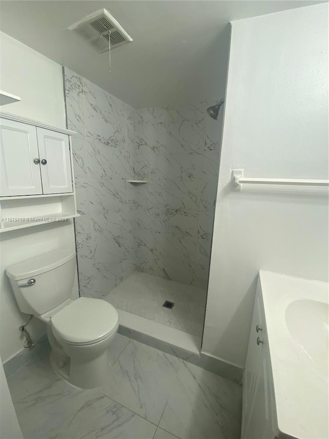 bathroom featuring vanity, tiled shower, and toilet