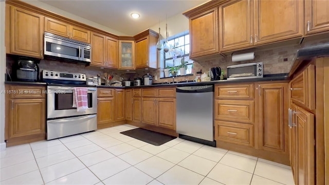 kitchen featuring light tile patterned flooring, appliances with stainless steel finishes, and backsplash