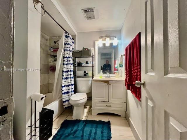 full bathroom featuring vanity, shower / tub combo with curtain, tile patterned flooring, and toilet