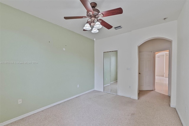 unfurnished bedroom featuring a closet, ceiling fan, and light colored carpet