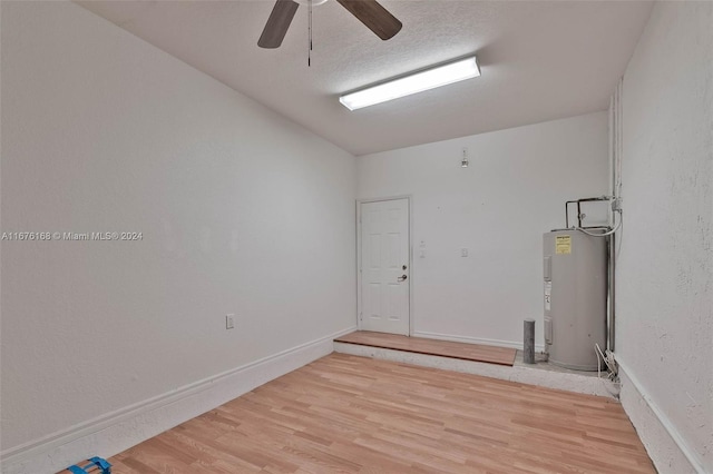 unfurnished room featuring ceiling fan, hardwood / wood-style flooring, and water heater