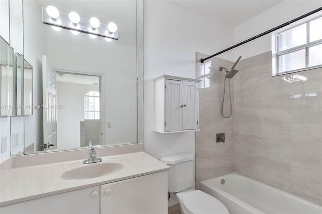 full bathroom featuring vanity, tiled shower / bath combo, toilet, and plenty of natural light