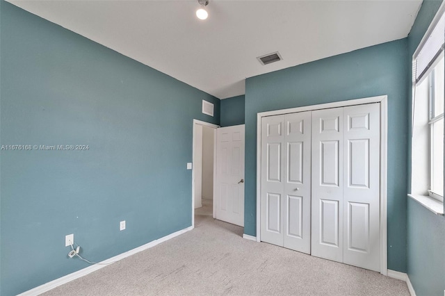 unfurnished bedroom with a closet and light colored carpet