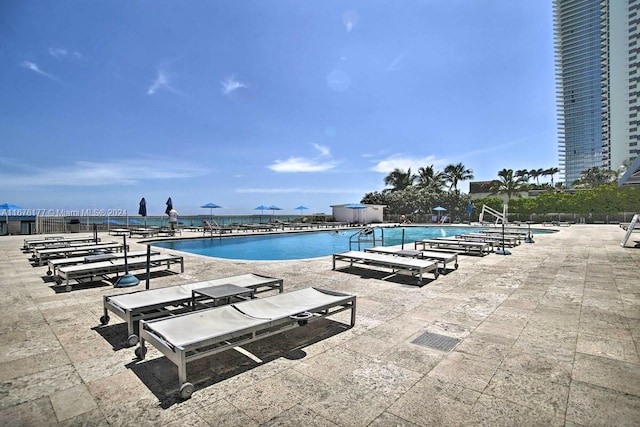 view of pool with a patio area and a water view