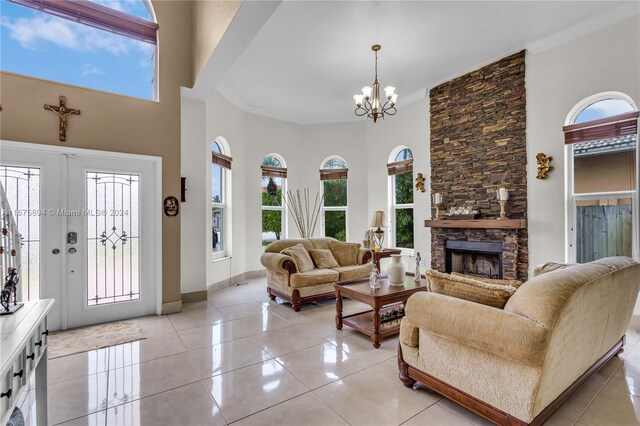 tiled living room with a fireplace, crown molding, a notable chandelier, and a towering ceiling