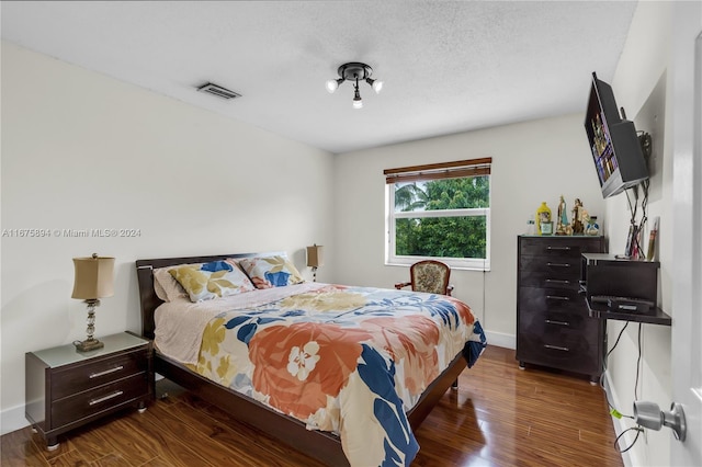 bedroom with a textured ceiling and dark hardwood / wood-style floors