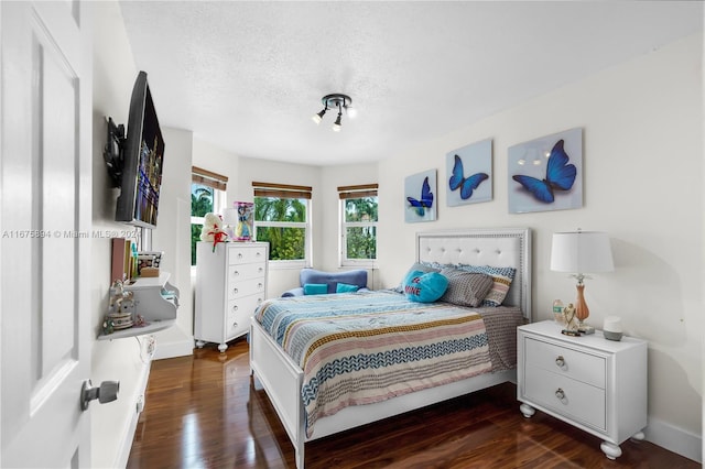 bedroom with dark hardwood / wood-style floors and a textured ceiling