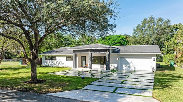 view of front of house featuring a garage, fence, decorative driveway, a front lawn, and stucco siding