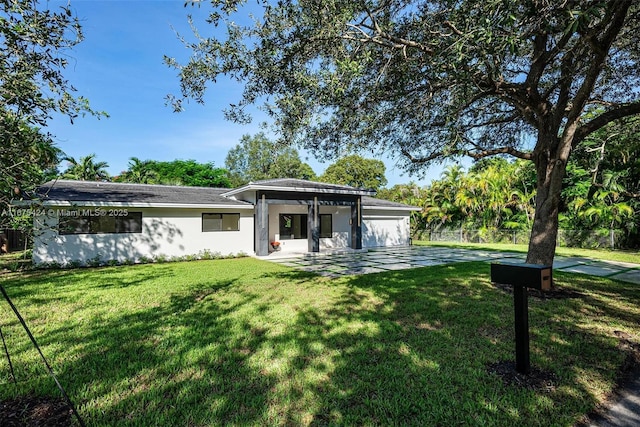 view of front of house featuring fence, a front lawn, and stucco siding