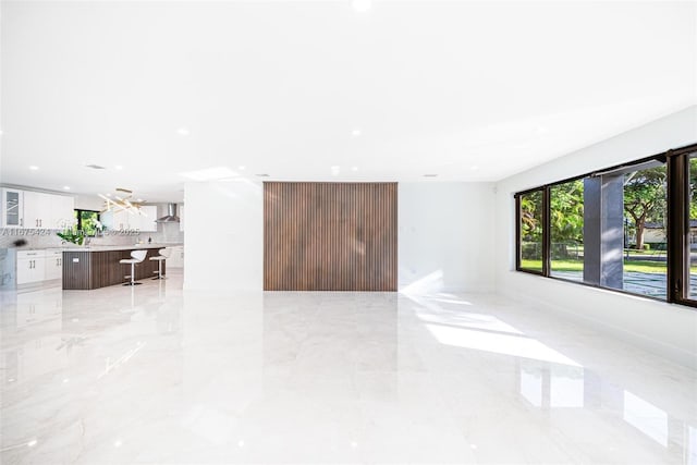 unfurnished living room with baseboards, marble finish floor, and recessed lighting