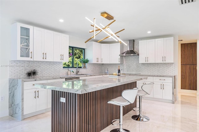 kitchen with wall chimney exhaust hood, a sink, glass insert cabinets, and white cabinets