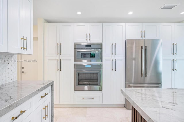 kitchen featuring white cabinets, tasteful backsplash, light stone counters, and stainless steel appliances