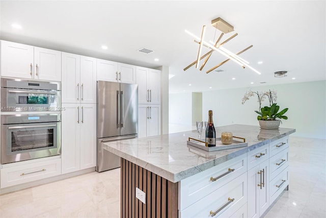 kitchen featuring stainless steel appliances, white cabinets, a kitchen island, and light stone counters