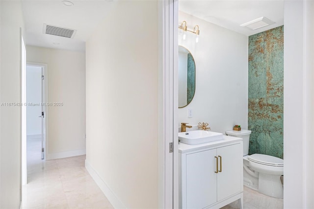 bathroom featuring toilet, vanity, visible vents, baseboards, and tile patterned floors