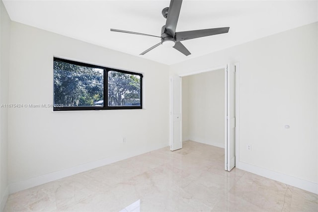 unfurnished bedroom featuring ceiling fan, marble finish floor, and baseboards