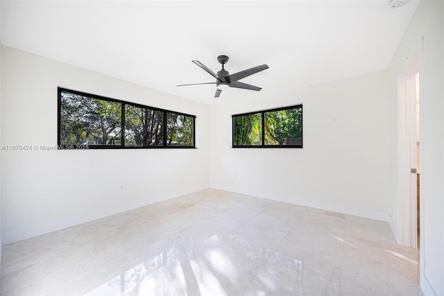 spare room featuring ceiling fan and baseboards