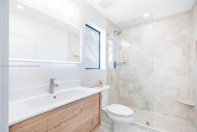 bathroom with a walk in shower, toilet, vanity, and visible vents