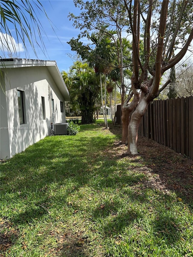 view of yard with fence and central AC unit