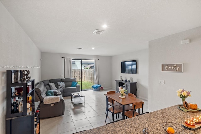 living area with baseboards, visible vents, a textured ceiling, and light tile patterned flooring