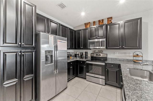 kitchen featuring light tile patterned floors, a sink, visible vents, appliances with stainless steel finishes, and light stone countertops