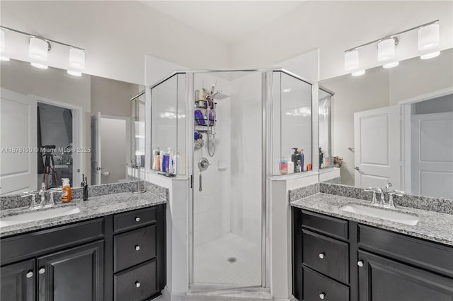 bathroom with a sink, two vanities, and a shower stall