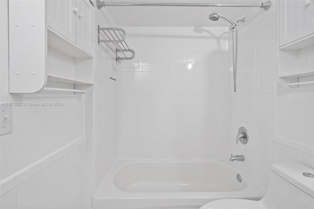 bathroom with tiled shower / bath combo and toilet